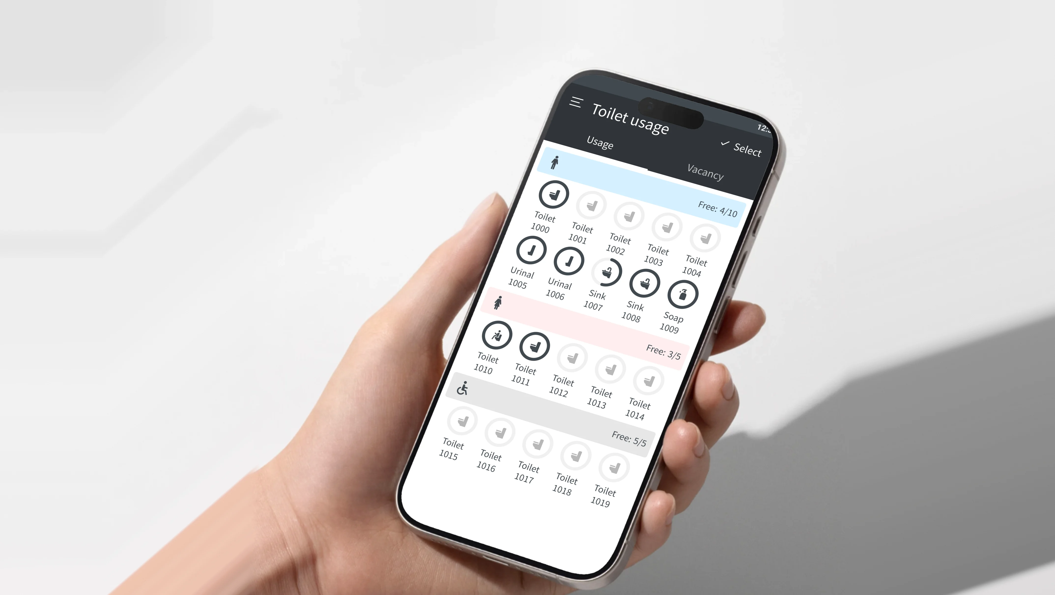 A hand holding a phone showing Lixil Toilet Cloud's Toilet usage screen - men's, women's and accessible restrooms, each booth a toilet icon ringed when in use, with how many are free - against a soft white wall